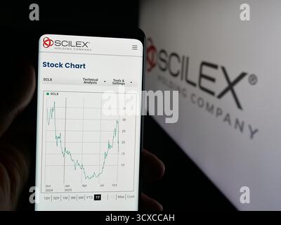 Dans cette illustration photo, une personne tient un téléphone portable avec la page Web de la société américaine de biopharmaceutique Scilex Holding Company sur l'écran devant le logo. Banque D'Images