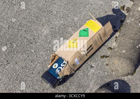 Cartouche d'oxyde nitreux « gaz risquant » moitié à l'intérieur d'une boîte en carton déchirée avec étiquettes de danger sur béton, concept de déchets industriels. Utrecht, pays-Bas. Banque D'Images