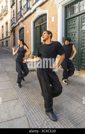 Groupe de jeunes danseurs modernes exécutant une routine énergique dans une rue de la ville, exprimant le mouvement et la passion tout en pratiquant leur forme d'art dans un Banque D'Images