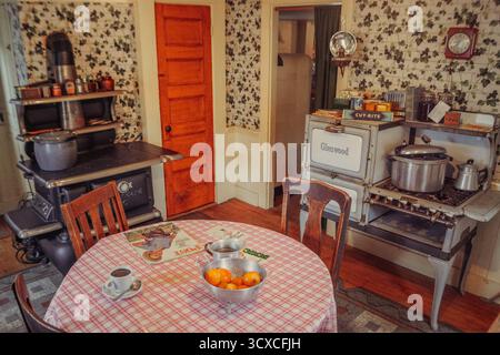 Intérieur de cuisine vintage à Strawbery Banke, Portsmouth, NH, avec vieux poêle, table en bois, papier peint floral et ustensiles historiques à la lumière du jour d'automne. Banque D'Images