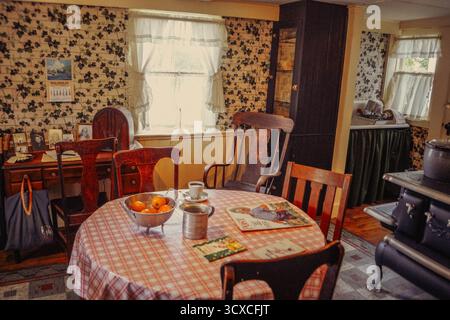 Intérieur de cuisine vintage à Strawbery Banke, Portsmouth, NH, avec vieux poêle, table en bois, papier peint floral et ustensiles historiques à la lumière du jour d'automne. Banque D'Images