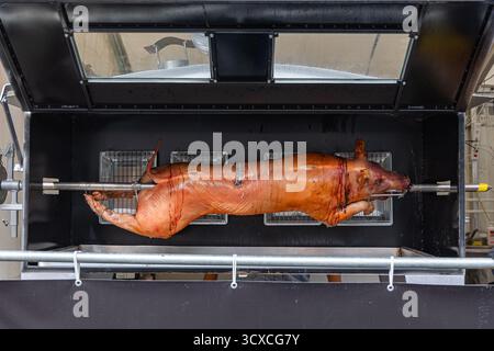 Un cochon de lait rôti sur une broche à griller moderne Banque D'Images