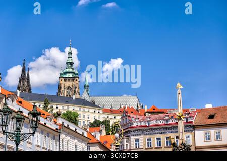 Vue sur le château de Prague et la cathédrale Saint-Guy s'élevant au-dessus des toits de la petite ville, avec des façades vibrantes et une architecture baroque. Banque D'Images
