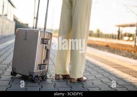Gros plan image de femme d'affaires élégante tenant une valise et debout à la gare. Espace de copie pour votre texte ou publicité. Banque D'Images