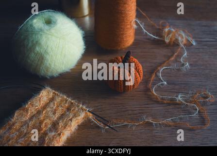 Chaussettes tricotées confortables sur les aiguilles avec citrouille tricotée. Boule de fil d'orange et de citron et aiguilles à tricoter. Procédé de tricotage de chaussettes en laine. Vibrations automnales douillettes Banque D'Images