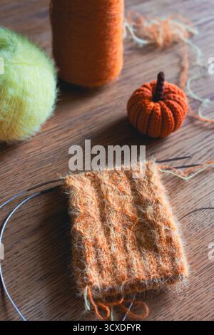 Chaussettes tricotées confortables sur les aiguilles avec citrouille tricotée. Boule de fil d'orange et de citron et aiguilles à tricoter. Procédé de tricotage de chaussettes en laine. Vibrations automnales douillettes Banque D'Images