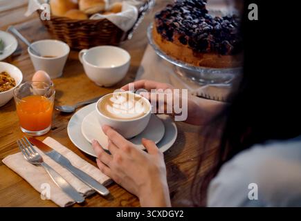 Petit déjeuner copieux avec cappuccino, gâteau aux baies et jus d'orange sur une table rustique en bois. Image pour les blogs alimentaires, les séjours à la ferme et l'hospitalité. Banque D'Images