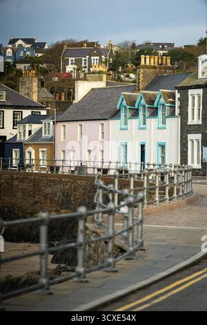Maisons colorées en bord de mer et l'hôtel Harbour House au-dessus d'une petite plage de sable dans le port de Portpatrick, Dumfries et Galloway, Écosse Banque D'Images