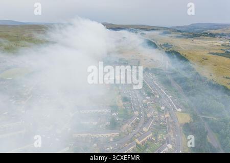 Feu de forêt sur la lande envoyant une épaisse fumée sur les maisons dans les Brecon Beacons, pays de Galles Banque D'Images