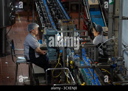 Deux travailleurs inspectent des bouteilles d'eau bonaqua sur la chaîne de production de l'usine d'embouteillage Swire Coca-Cola le 14 octobre 2025 à Hong Kong. (Photo de Vernon Yuen/Nexpher images) Banque D'Images