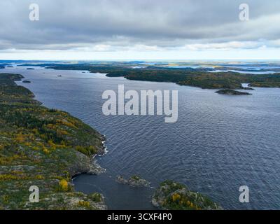 Plan aérien large surplombant une grande crique ou baie d'eau agitée et sombre, bordée par une côte accidentée et des collines couvertes d'automne dense vert et doré Banque D'Images