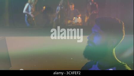 Regardant l'homme barbu en chemise raglan regardant un groupe de rock sur le moniteur dans la salle de projection, espace de copie Banque D'Images