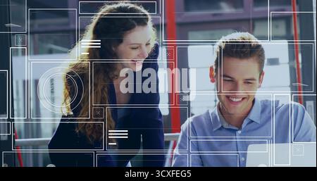 Collaboration collègues discutant des détails sur ordinateur portable dans un bureau moderne, avec superpositions numériques Banque D'Images