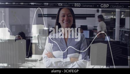 Femme professionnelle croisée dans le bureau ouvert avec des graphiques de devises sur la cloison de verre Banque D'Images