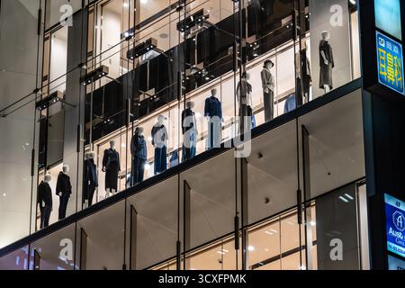 Tokyo, Japon - 5 août 2024 : une photo de nuit capture des mannequins habillés dans des tenues élégantes, présentés dans une vitrine de Ginza, Tokyo. Le moderne Banque D'Images