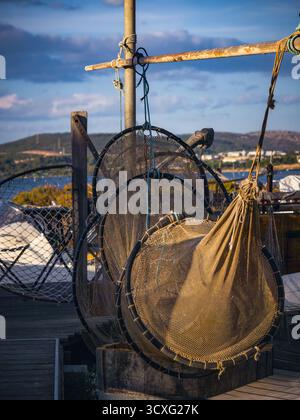 Filets de pêche circulaires traditionnels séchant sur la jetée en bois dans le village méditerranéen, lumière de fin d'après-midi Banque D'Images