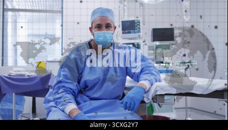 Chirurgien assis portant des gommages sur le bord de la table au bloc opératoire avec moniteur vital, superposition cartographique Banque D'Images