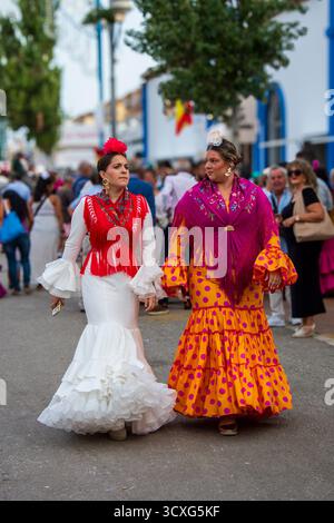Fuengirola, Málaga, Espagne. 12 octobre 2025. Jeunes femmes en robes de flamenco traditionnelles marchant à travers le parc des expositions de Fuengirola Banque D'Images