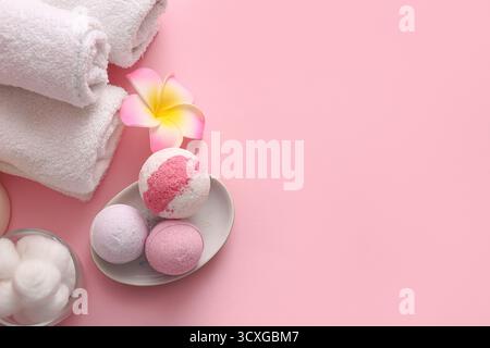 Composition with clean towels, plumeria flower and bath bombs on pink background, closeup Banque D'Images