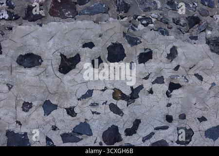 Gros plan texture d'un vieux mur de pierre méditerranéen avec plâtre clair craquelé et roches volcaniques Banque D'Images