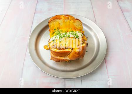 Nature morte avec un hamburger ouvert montrant son intérieur juteux, sur un fond de marbre avec des herbes fraîches Banque D'Images