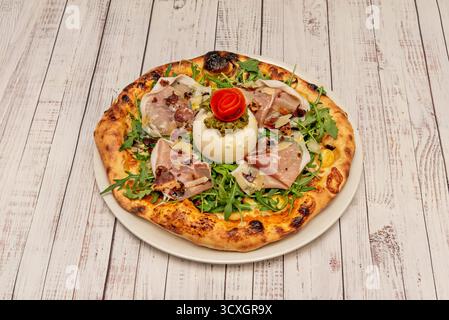 Pizza capricieuse avec jambon serrano, champignons sautés, artichauts, et un œuf poché au centre Banque D'Images