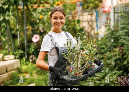 Une femme s'engageant dans des activités de jardinage avec de belles plantes en pot dans un environnement de jardin luxuriant Banque D'Images