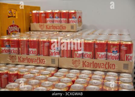 Porec, Croatie - 31 mai 2025 : plusieurs boîtes en carton et canettes de la marque de bière croate Karlovacko empilées sur des étagères dans la zone de stockage au détail. Rouge et Banque D'Images