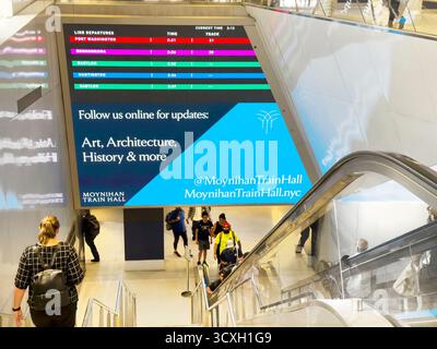 Panneau de départ numérique LIRR au-dessus de l'escalator et des escaliers, Moynihan train Hall, Pennsylvania Station, Manhattan, New York City, New York, États-Unis Banque D'Images