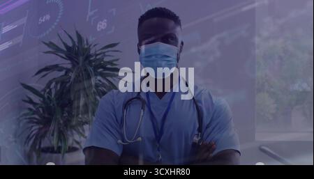 Médecin debout portant des gommages bleu clair et un masque chirurgical dans la salle d'examen avec stéthoscope et badge Banque D'Images