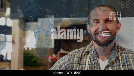 Affichage de la superposition de la carte numérique, artisan barbu dans la chemise à carreaux et tablier dans l'atelier de bois, espace de copie Banque D'Images