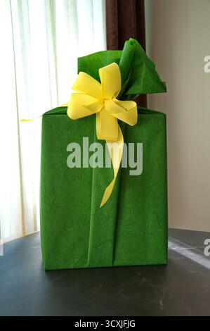 Cadeau enveloppé dans du papier vert avec ruban jaune sur la table Banque D'Images