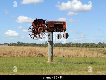 South Kolan, Queensland, Australie - 11 juin 2024 : vieux tracteur rouillé monté sur un poteau en bois dans le cadre de l'attraction touristique Jim's Row of Machinery Banque D'Images