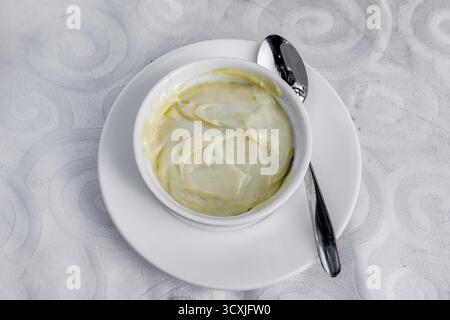 Cette image montre un gros plan d'un bol de sauce crémeuse avec une cuillère, parfait pour les projets culinaires Banque D'Images