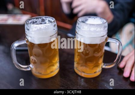 Prague, République tchèque, 7 août 2023. Deux tasses de bière côte à côte. Dans le fond flou, les mains de ceux qui les apprécient. Un style de vie de Sha Banque D'Images