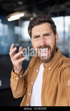 Homme barbu éprouvant la colère et la frustration, criant et faisant des gestes lors d'un désaccord ou d'un conflit, capturant son expression angoissée et inte Banque D'Images