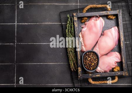 Filets de cuisses de poulet crus dans un plateau en bois. Fond noir. vue de dessus. Banque D'Images