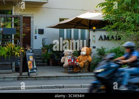 Deux ours en peluche doux assis à une table, boire Aperol dans un café de rue italien Ama 18 chambres hôtel à Côme. Italie, Côme - 17 juillet 2025. Banque D'Images
