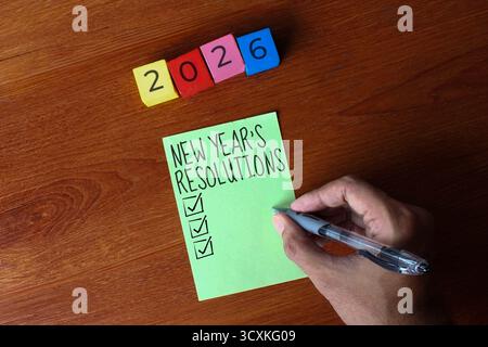 Image vue du dessus du papier vert avec les mots 'RÉSOLUTIONS DU NOUVEL AN' écrit dessus et blocs colorés avec le numéro 2026. Concept de résolutions du nouvel an. Banque D'Images