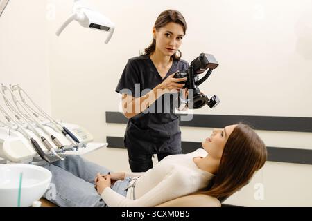 Femme dentiste photographiant avec un appareil photo professionnel le résultat de son travail en clinique. Banque D'Images