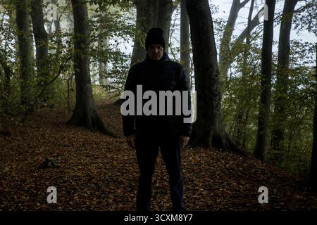 Homme effrayant debout en face de vous regardant sur le chemin de marche dans la scène de forêt sombre, harceleur vous suivant, scène effrayante halloween Banque D'Images