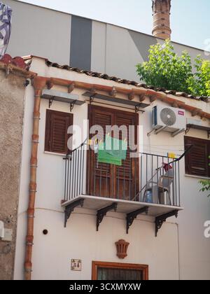Petit balcon avec serviette verte et volets en bois sur une façade de maison traditionnelle à Palerme, Sicile, Italie Banque D'Images
