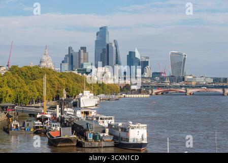 Quartier financier de Londres sur la ligne d'horizon derrière Temple Pier et bateaux sur la Tamise. Gratte-ciel modernes et dôme de la cathédrale Saint-Paul Banque D'Images
