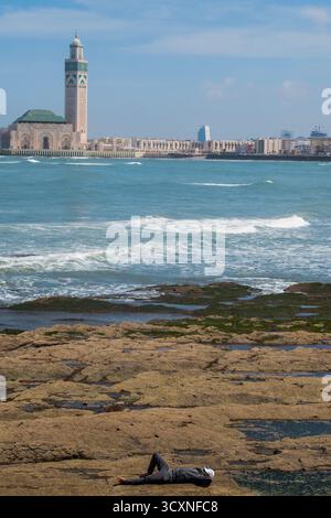 Casablanca, Maroc, Afrique : homme avec une balle de baseball reposant sur la plage pendant le ramadan ramadan devant l'océan Atlantique et la mosquée Hassan II (1993) Banque D'Images