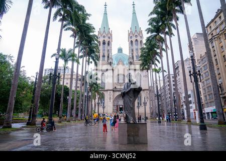 Une vue du monument de l'Apôtre Paul devant la cathédrale métropolitaine de Sé un jour de pluie ; les touristes peuvent être vus en visite malgré la météo Banque D'Images