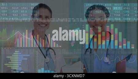 Debout deux médecins portant une blouse de laboratoire et des gommages examinant des tableaux de données en clinique, avec des stéthoscopes Banque D'Images