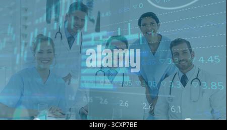 Équipe médicale collaborant dans les gommages et les manteaux examinant les graphiques de données en clinique, avec ordinateur portable Banque D'Images