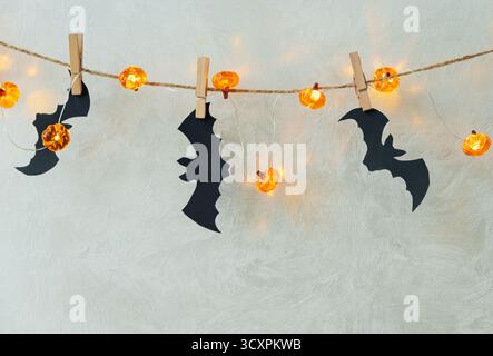 Guirlande d'Halloween avec lumières de citrouille et découpes de chauve-souris sur un mur texturé Banque D'Images