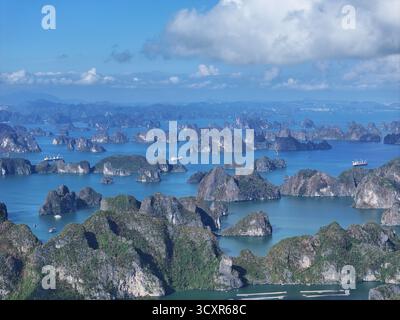 Ha long Bay montrant des formations karstiques calcaires s'élevant de l'eau émeraude, créant un paysage marin unique et spectaculaire avec plusieurs bateaux naviguant Banque D'Images