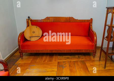 L'image présente un cadre intérieur confortable et vintage avec un canapé rouge vif et un coussin pouf la pièce respire la chaleur, idéal pour la décoration de la maison, les meubles Banque D'Images